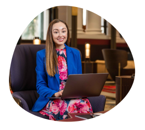 Isabella Shoard, MBA graduate sitting on chair with laptop at UQ Brisbane City Campus 