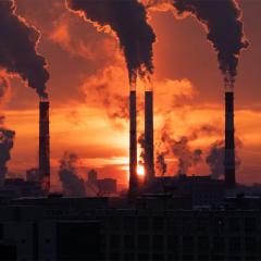 factory emitting fumes from smokestacks at dusk