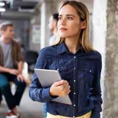 Person holding an ipad, looking into the distance
