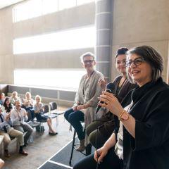 A woman is answering a question on a panel 