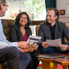 Two MBA students sitting with an academic in the new UQ Brisbane City Campus all holding papers 