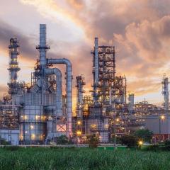 a factory with tall pipes and a field of grass