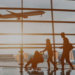 Man and woman walking through airport near window. Plan flies in background with sun shining through. 