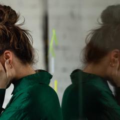 Young sad woman in office, with head in hands.