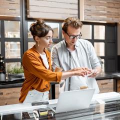 A man and woman in a workplace stand next to a laptop