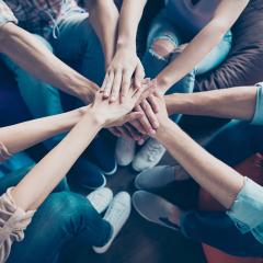 people in a circle placing hands on top of each other in the middle